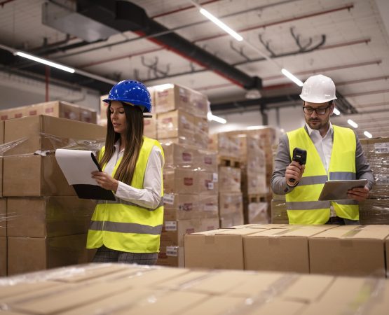 Warehouse workers using bar code scanner and tablet and checking goods inventory.
